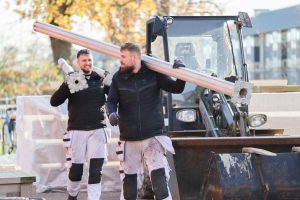 Glade tømrere fra Lars Printz A/S, der bærer store soldater hen til et projekt, hvor der skal skiftes bundremme på Mærsehuset.